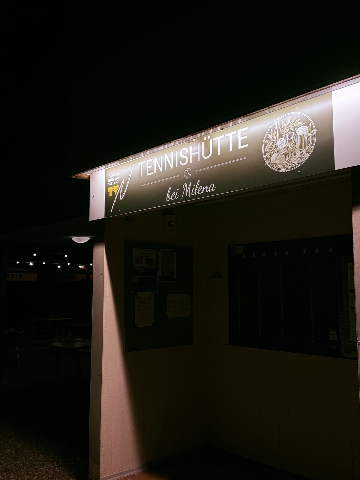 Beleuchtetes Schild der Tennishütte bei Nacht